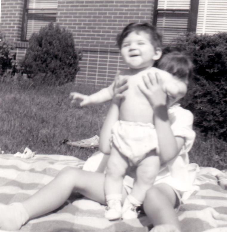 Baby Rhonda with a neighbor on a blanket in the yard laughing